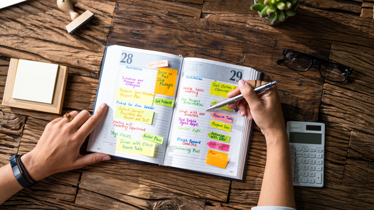 Why January is the Best Time to Set Pest Control Resolutions A woman writes pest control resolutions on a calendar using a pen and paper, seated at a wooden table.