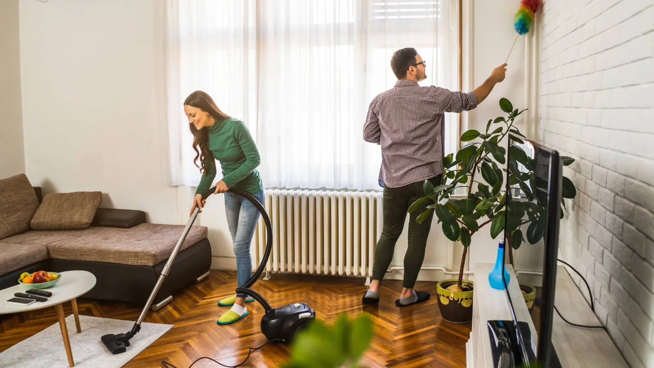 Love Your Home Keep It Rat-Free This February A couple diligently cleaning a room with a vacuum, emphasizing a rat-free environment and a love for their home.