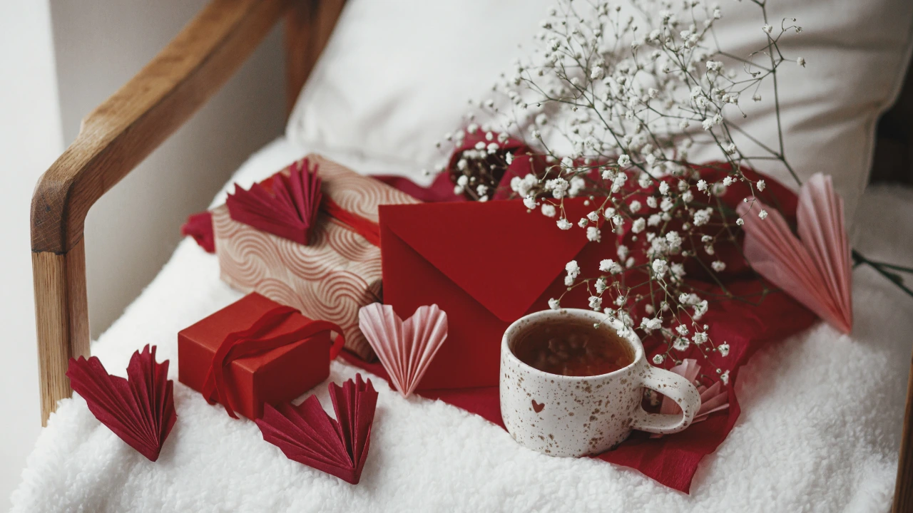 Pest-Free Romance Creating a Cozy and Clean Home This Valentine’s A cup of coffee, a red heart, and a gift box on a bed, symbolizing a cozy and clean Valentine's Day atmosphere.