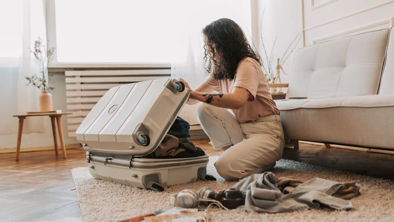 A Pest-Free Holy Week How to Prepare Your Home Before Leaving for Vacation A woman on the floor with a suitcase, illustrating travel during a pest-free Holy Week celebration.