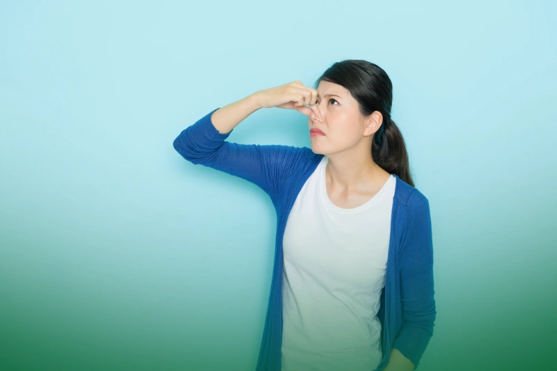 Unpleasant Odors a woman in blue cardigan covering her nose and acting for bad smell
