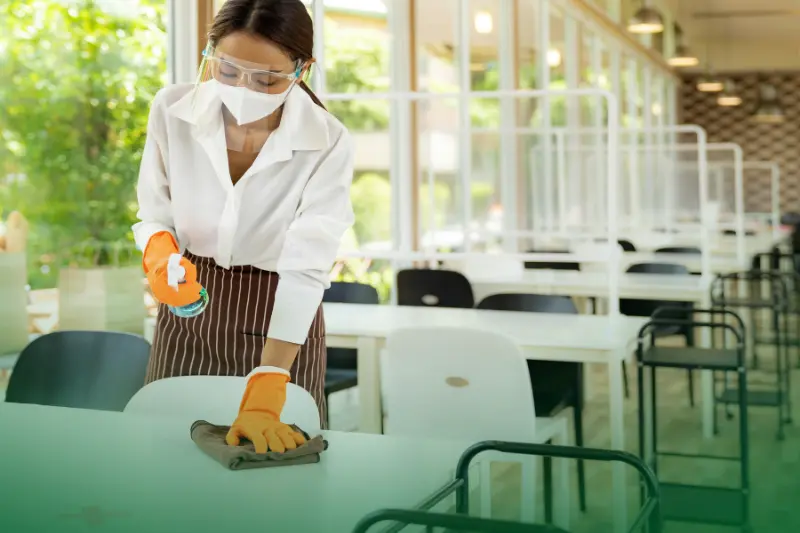Upholding Hygiene Standards a woman cleaning a table in a restaurant